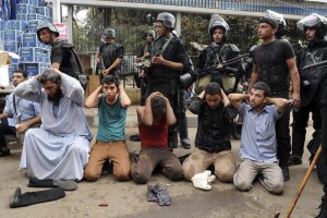 Varios miembros de las fuerzas de seguridad egipcias vigilan a un grupo de manifestantes arrestados 