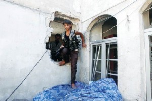 Un combatiente de 15 aos del Ejrcito de Siria Libre atraviesa un agujero en una pared en la ciudad