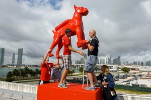 Personas instalan perros gigantes creados por Wiliam Sweetlove permanecen e el techo de Museo Infant