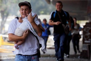 Un hombre corre con un beb a cubrirse de los gases lacrimgenos y piedras durante los disturbios en