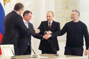 El presidente Putin (centro) estrecha las manos del premier de Crimea, Sergei Aksyonov (frente, izq.