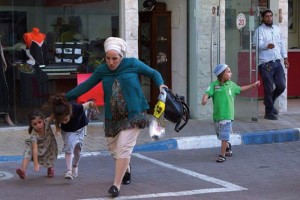 Una familia israel corre para ponerse a salvo de un ataque con cohetes por parte de Hamas, en Sdero