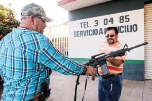El fundador de las autodefensas en Michoacn, Hiplito Mora Chvez (derecha), entrega su arma a un p